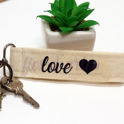 Chaveiro tecido bege com chave e planta em vaso branco