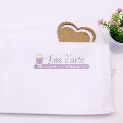 Toalha branca acolchoada com etiqueta Fios d'arte, porta-corações em madeira e vaso com flores cor-de-rosa