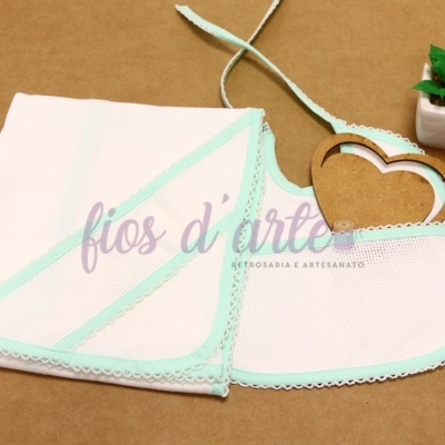 Toalha de rosto branca com acabamento em crochê verde claro ao lado de pequena planta em vaso branco