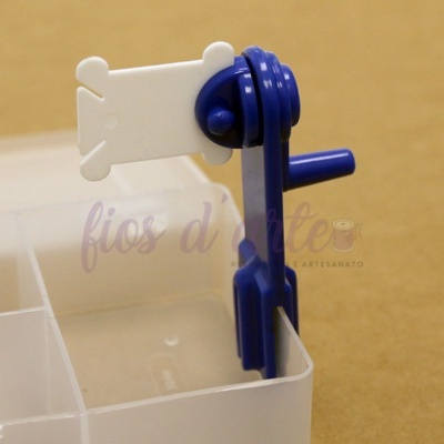 Prendedor plástico azul e branco em recipiente transparente sobre fundo bege