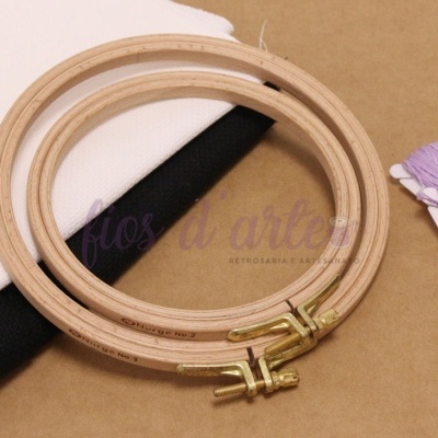 Bastidores de bordado, tecidos branco e preto, fios lilás e roxo