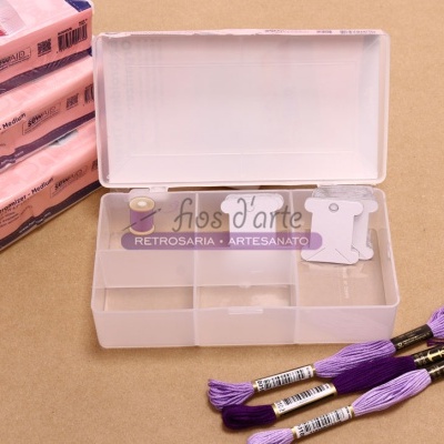 Estojo plástico com compartimentos e lãs roxas ao lado de pacotes rosas