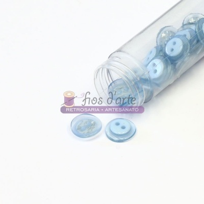 Frasco plástico com botões azuis claros derramados sobre fundo branco