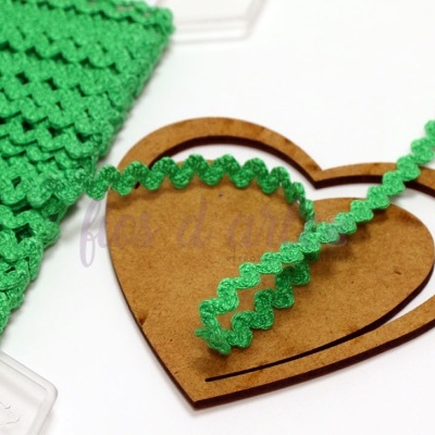 Fita verde ondulada sobre base de corte em forma de coração em madeira