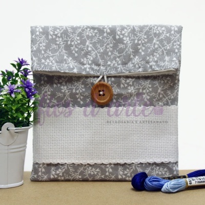 Bolsa de tecido cinzento com padrão floral, botão de madeira, planta em vaso branco e novelos de linha azul