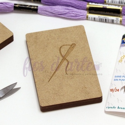 Materiais de artesanato: fio lilás, cartão com desenho de agulha, tesoura, embalagem de agulhas PONY.