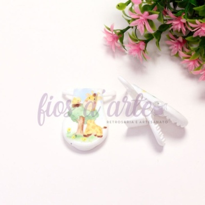 Brincos de resina com coelho pintado à mão e fecho branco, perto de flores cor-de-rosa e folhas verdes.