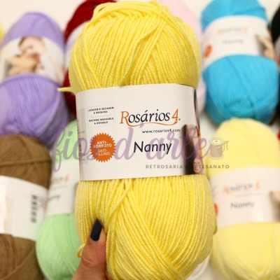 Novelo amarelo de lã Rosários 4 coleção Nanny com outros novelos coloridos ao fundo