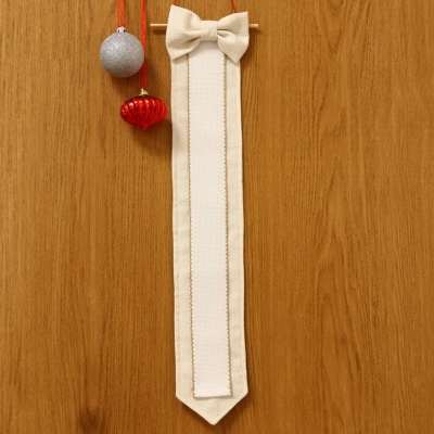 Marcador de páginas branco com laço pendurado em parede de madeira com bolas decorativas