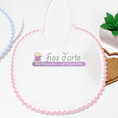 Babete branco com contorno rosa em tecido, planta verde em vaso branco e coração de madeira