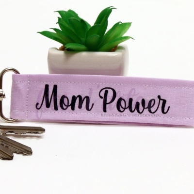Chaveiro lilás com texto Mom Power, conjunto de chaves e planta artificial