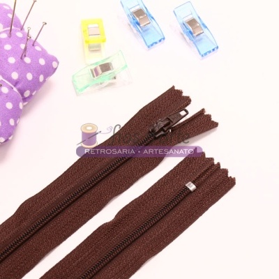Acessórios de costura castanhos, clips coloridos e alfineteiro roxo com bolinhas