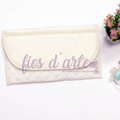 Carteira de tecido branco com texto Fios d'arte, dois chuchas coloridos, vaso com flores artificiais