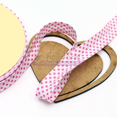 Fita de tecido branca com bolinhas cor-de-rosa enrolada em carretel amarelo e cartão castanho em forma de coração