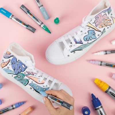 Sapatilhas brancas customizadas com desenhos coloridos e canetas ao redor