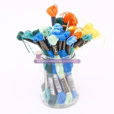 Novelos de linha de bordado colorida num recipiente de vidro