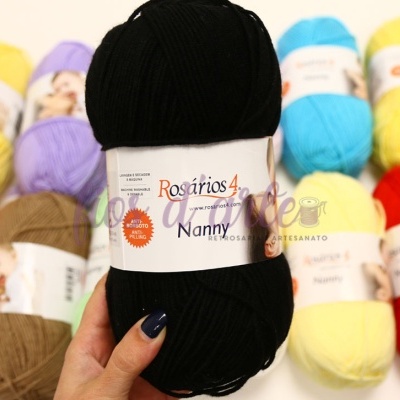 Novelo de lã preta Rosários 4 Nanny com vários novelos coloridos ao fundo