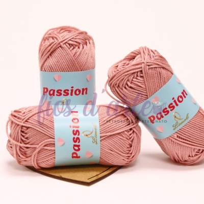 Três novelos de fio de lã rosa claro com rótulo azul com texto passion