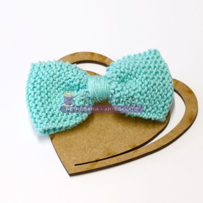 Laço tricotado azul claro sobre suporte de papelão em forma de coração