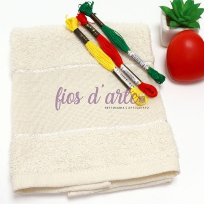Toalha branca com novelos de linha colorida e vaso com planta e coração vermelho