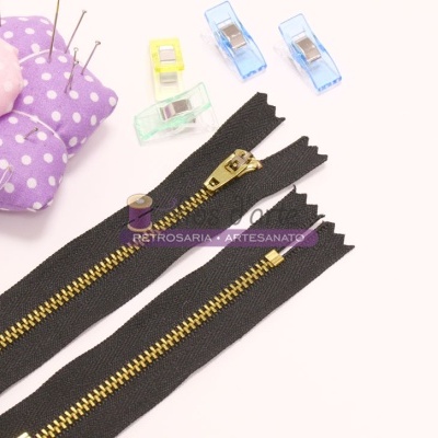 Fecho éclair preto, clips coloridos e alfineteiro floral lila sobre fundo branco