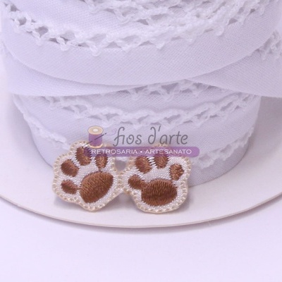 Rolos de fita branca rendada com patch bordado de patas castanhas e etiqueta de marca