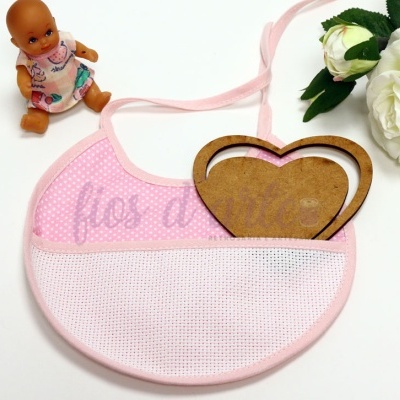 Babete de bebé rosa com padrão de pontos, fitas para amarrar, boneca e rosa branca ao lado