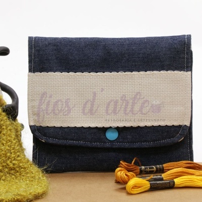 Bolsa azul com aba de linho cru e botão azul, novelo de lã verde e linha de bordado amarela
