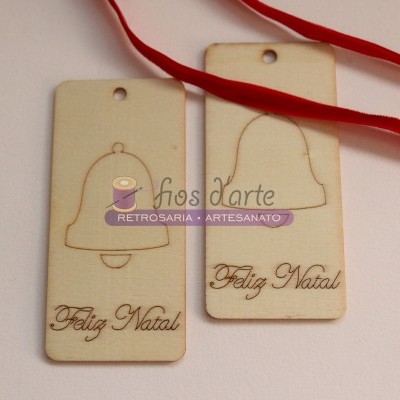 Etiquetas de madeira com desenhos de sino e texto 'Feliz Natal' com fita vermelha