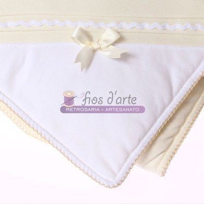 Manta bege com borda branca, laço e logo 'fios d'arte'