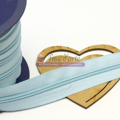 Fita de zíper azul claro em carretel azul sobre base em forma de coração de madeira com etiqueta