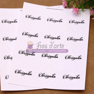 Papéis brancos com 'Obrigada' em letra cursiva preta e flores cor-de-rosa junto a um logótipo colorido