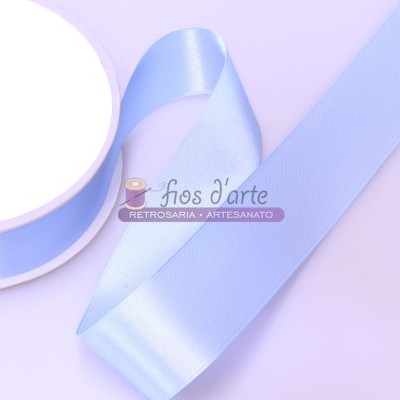 Fita de cetim azul clara enrolada em carretel branco sobre fundo lilás