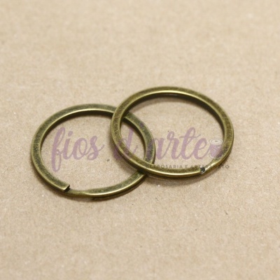 Duas argolas metálicas bronze sobre cartão castanho com texto