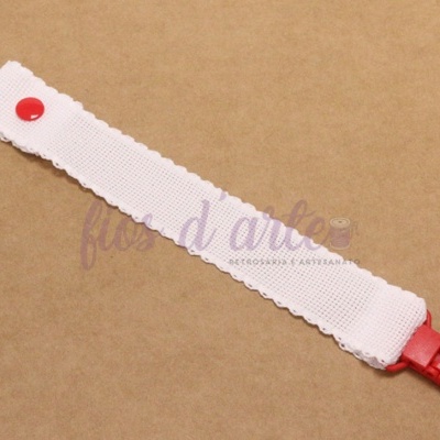 Presilha para cabelo branca com detalhes vermelhos sobre superfície castanha clara