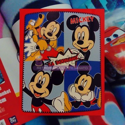 Manta com estampado de Mickey Mouse em quatro quadrantes coloridos e embalagem com tema de carros.