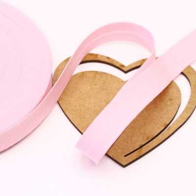 Rolo de fita rosa e coração de cartão sobre fundo branco