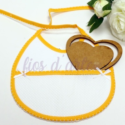 Babete branco com borda amarela e coração de madeira ao lado