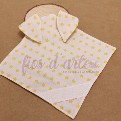 Pano branco com estrelas amarelas e orelhas de tecido sobre superfície castanha