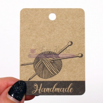 Etiqueta de papel castanho com novelo de lã e agulhas e a palavra Handmade