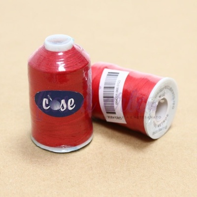 Dois carretéis de linha vermelha com etiquetas e código de barras sobre fundo castanho