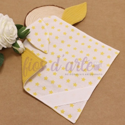 Toalha de bebé amarela e branca com padrão de estrelas e flor branca ao lado