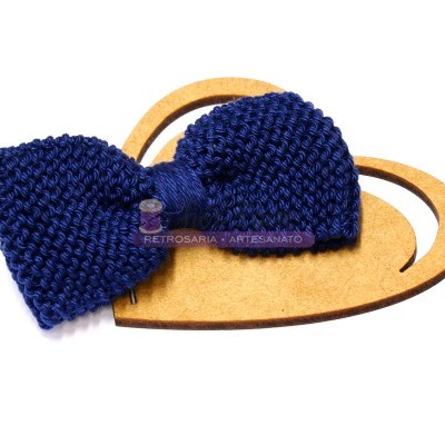 Laço de cabelo azul escuro em crochê sobre base em forma de coração castanha.