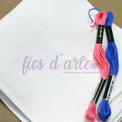 Pano branco com dois novelos de linha rosa e azul sobre superfície castanha