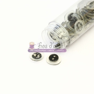 Frasco plástico com botões prateados com desenho preto sobre superfície branca