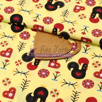 Tecido amarelo com padrão de galos pretos, corações vermelhos e flores coloridas