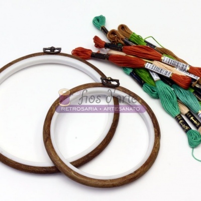 Dois bastidores de madeira para bordado com várias meadas de linha de algodão coloridas sobre fundo branco