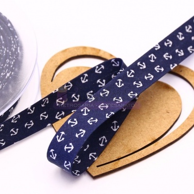 Fita azul-marinho com âncoras brancas sobre madeira em forma de gota e rolo de fita