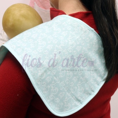 Manta azul claro com padrão branco usada segurando boneca