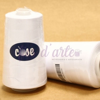 Cones de linha de costura branca com rótulo 'cose' sobre superfície castanha